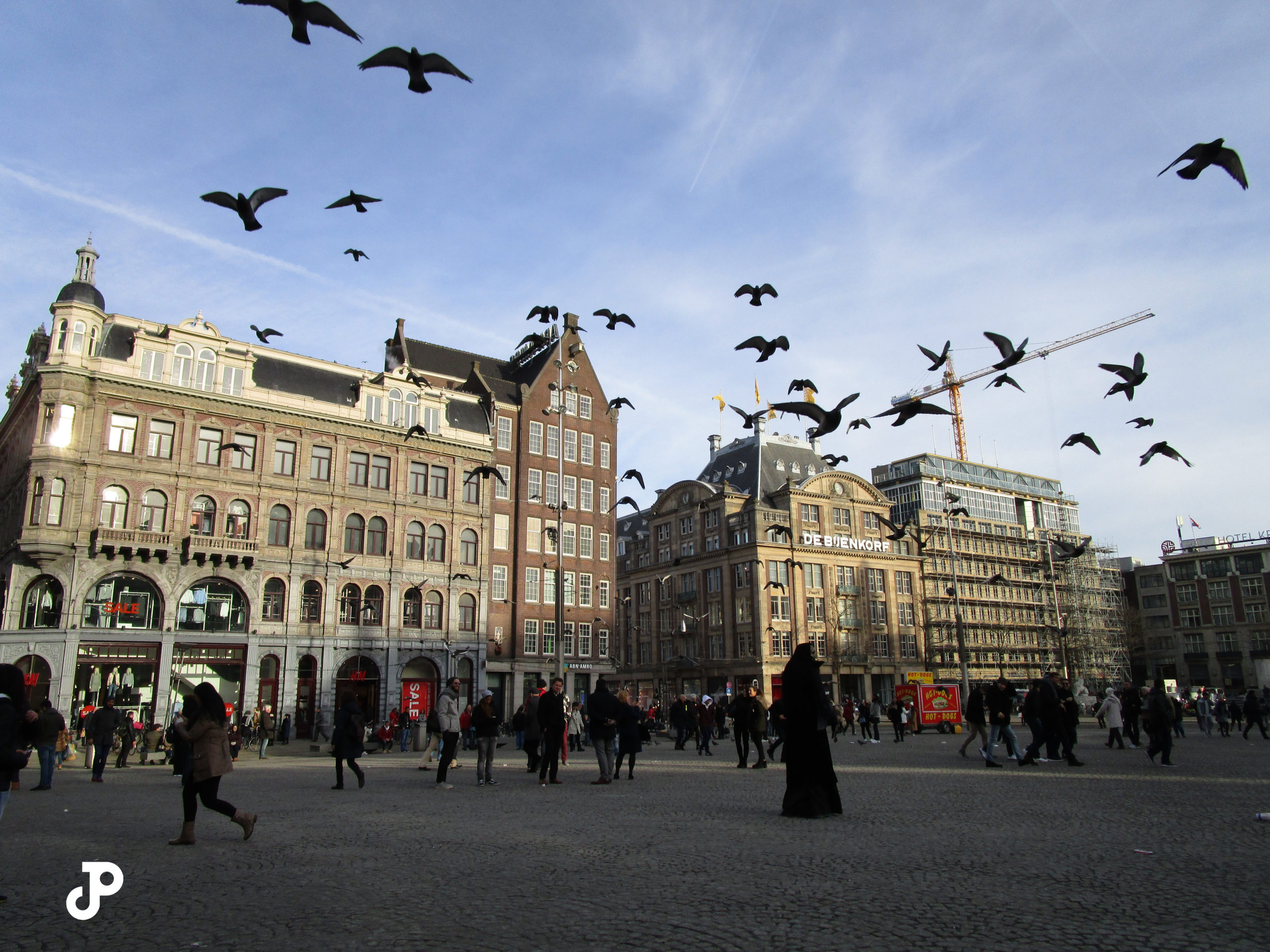 Birds flying overhead a busy public square filled with tourists