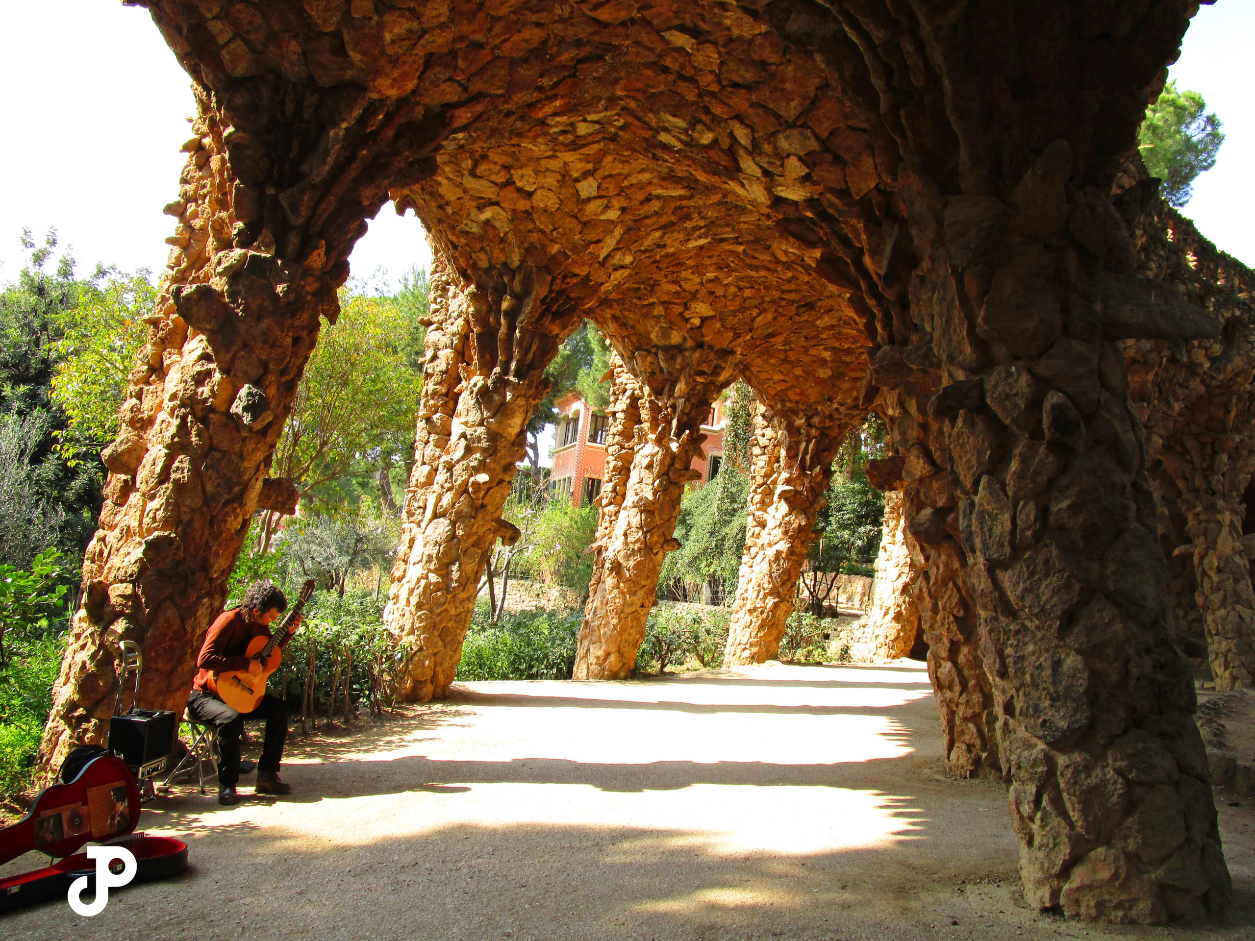 a man playing guitar beneath a stone archway in Park Guell