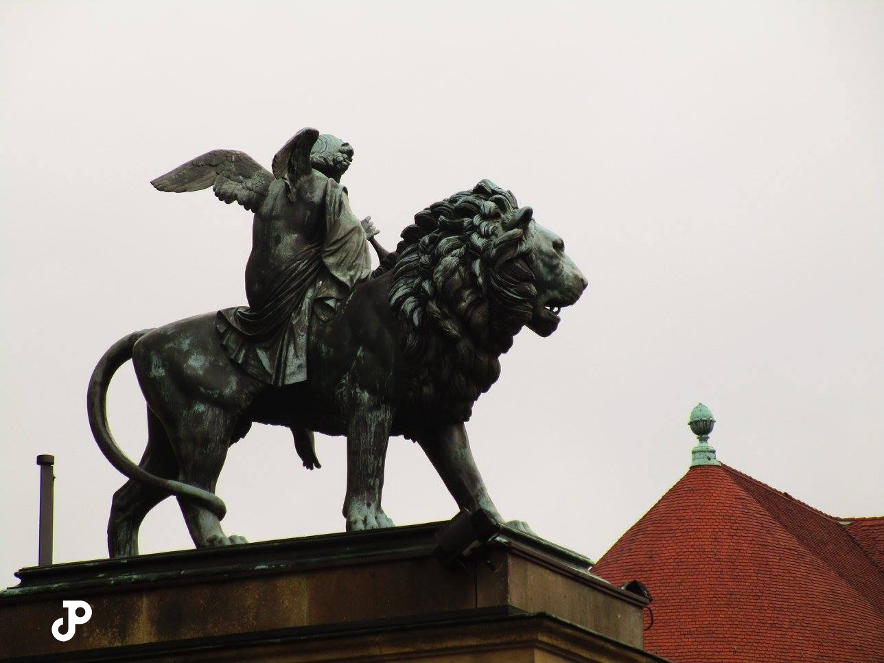 a green copper statue of a lion with an angel sitting on its back