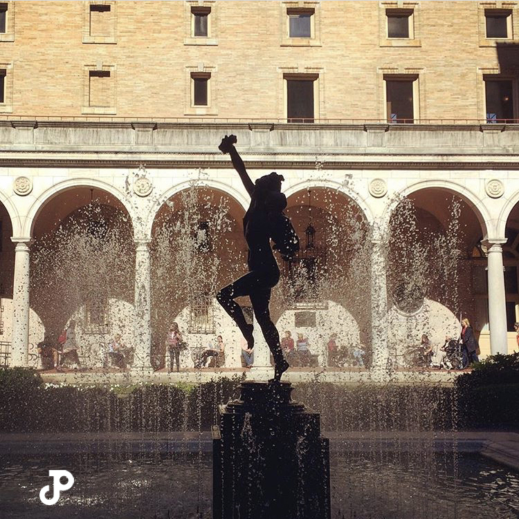 a silhouette of a statue in a sunny courtyard within the Boston Public Library