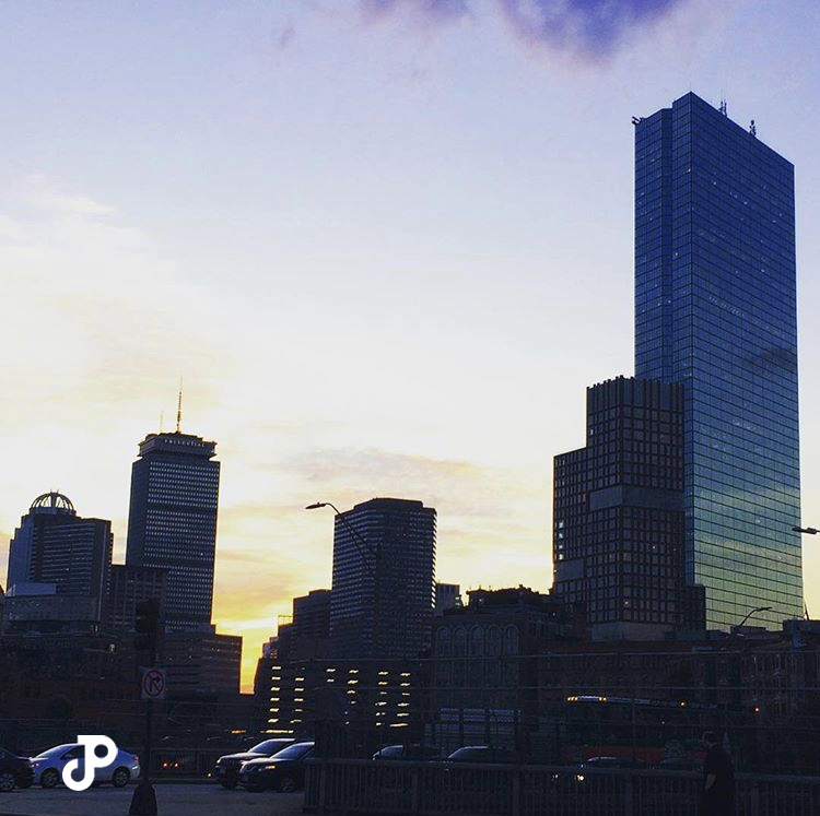 a purple sunset behind the darkened Boston skyline