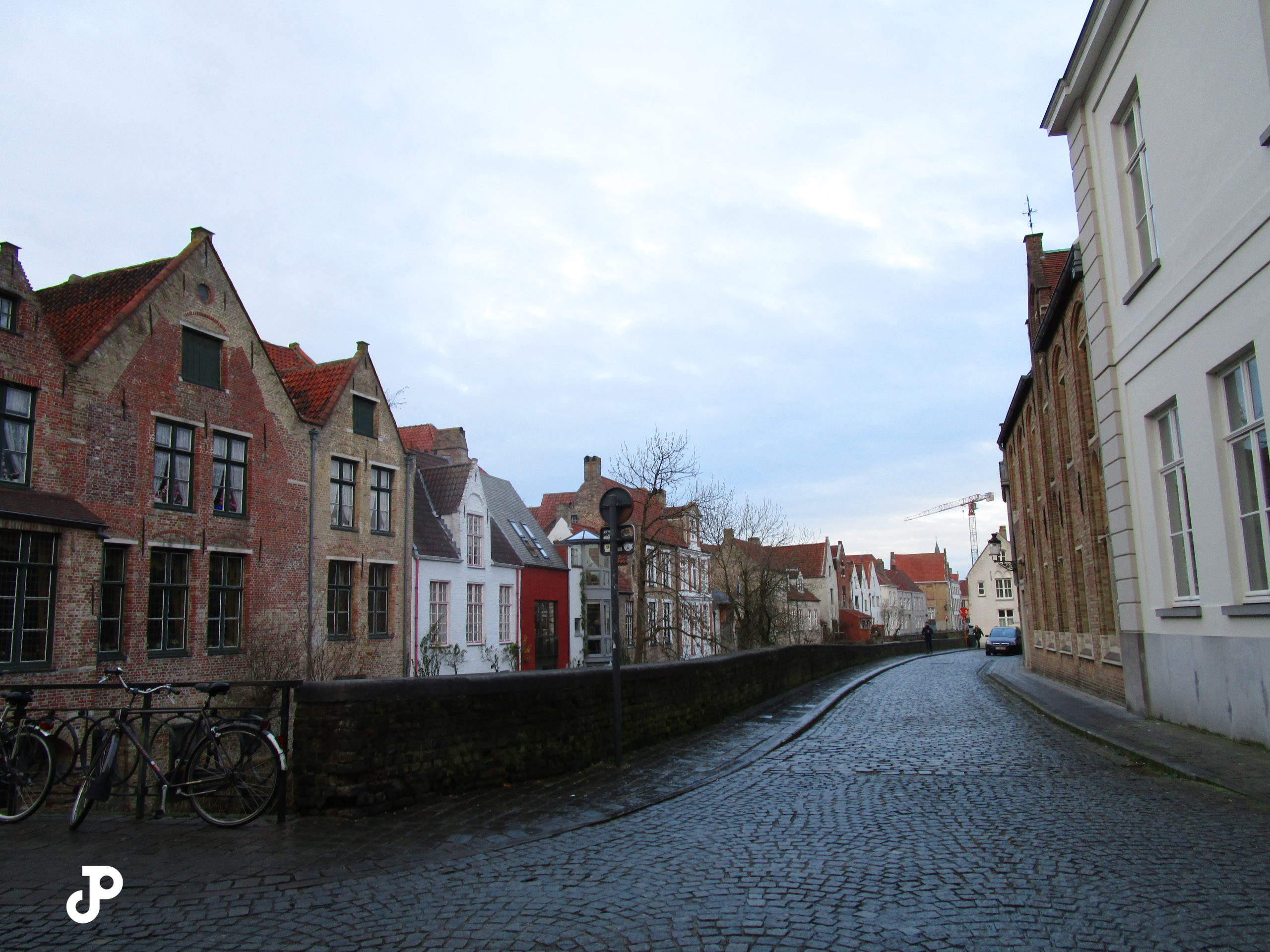 a cobblestoned street lined with old brick buildings with pointed rooves