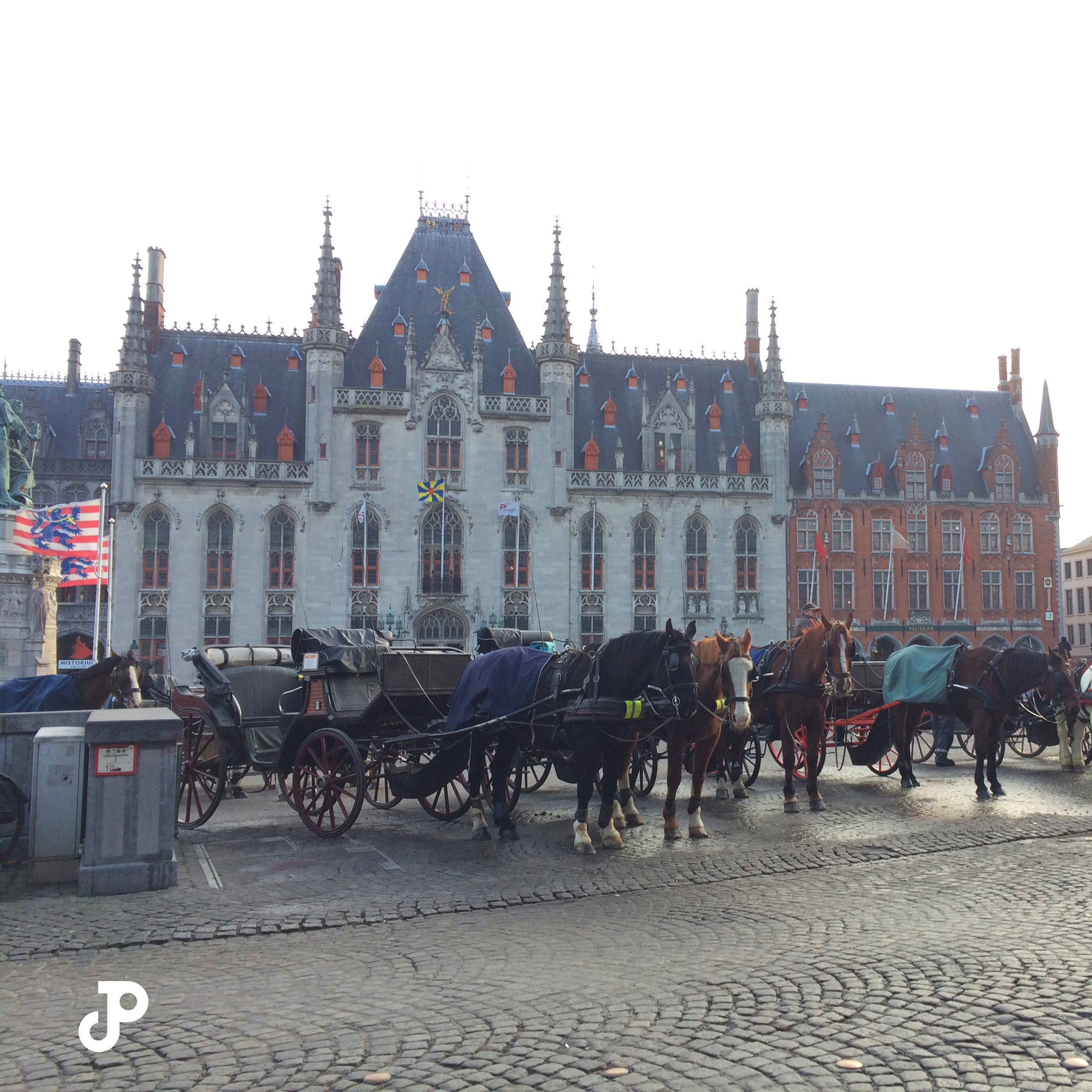 horses and carriages lined up in Burg Square, with the Bruges City Hall in the background