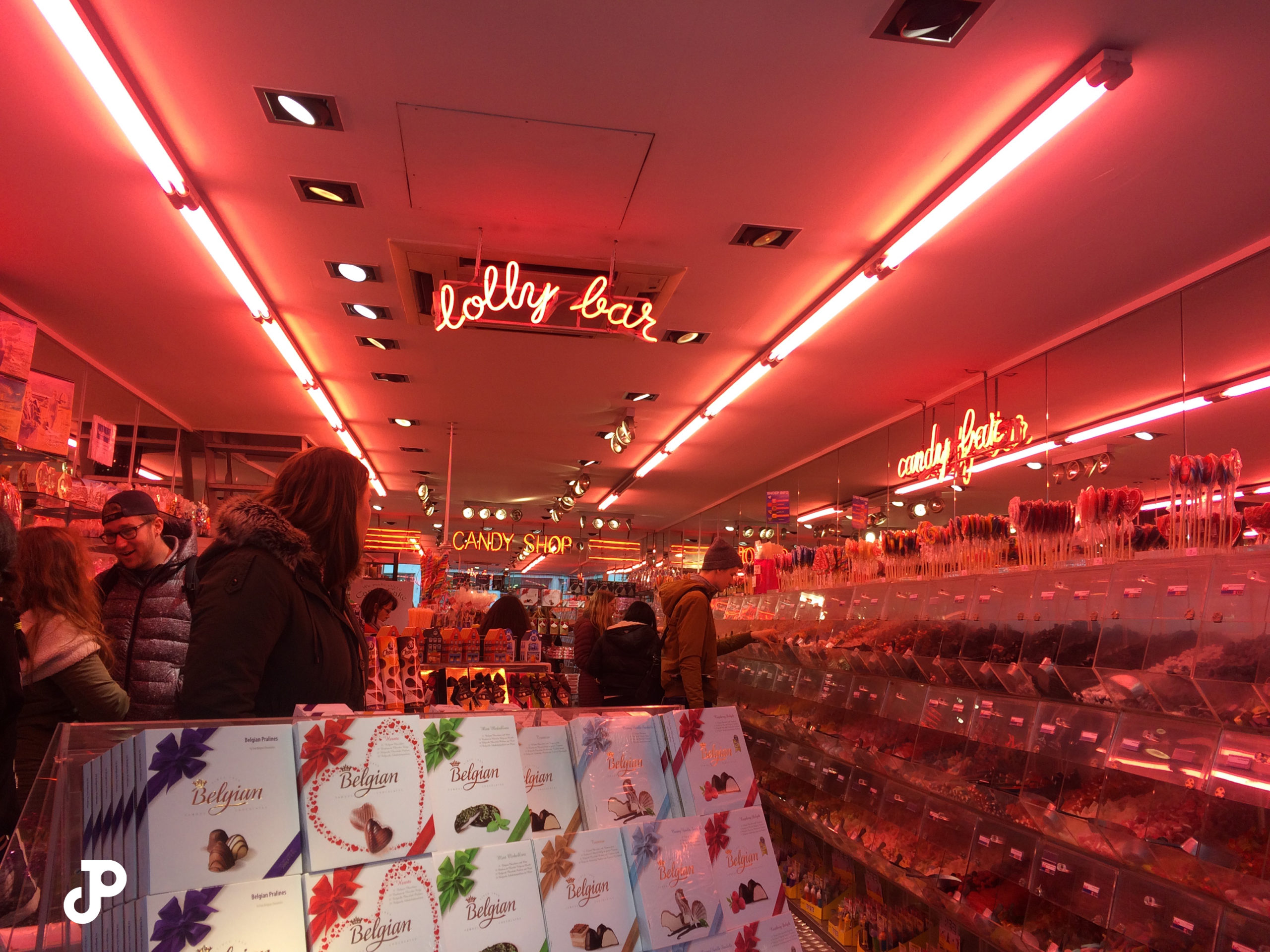 a candy shop washed in pink light from vibrant neon lights lining the ceiling