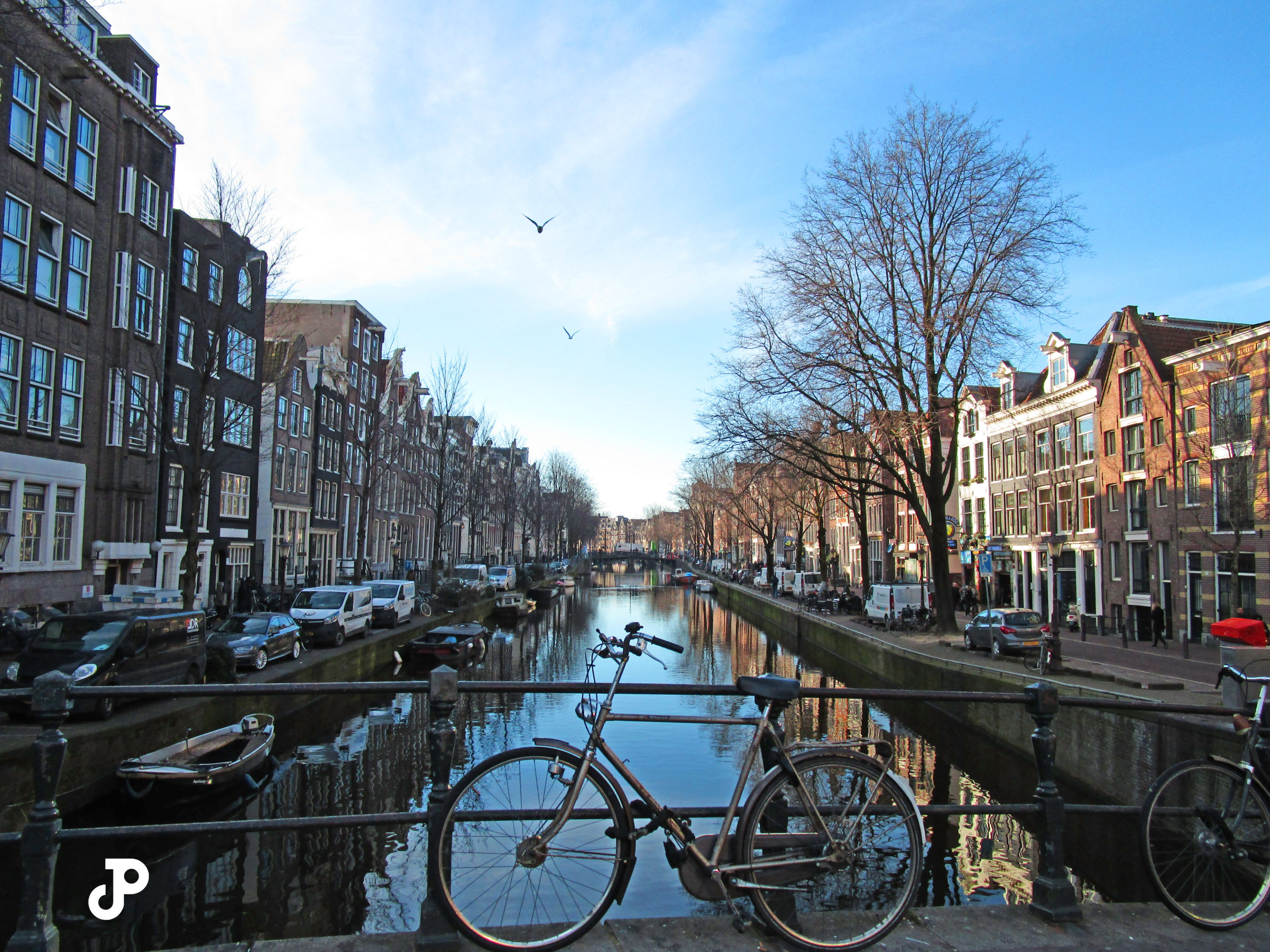 a bicycle leaning against a railing, on a bridge over an Amsterdam canal