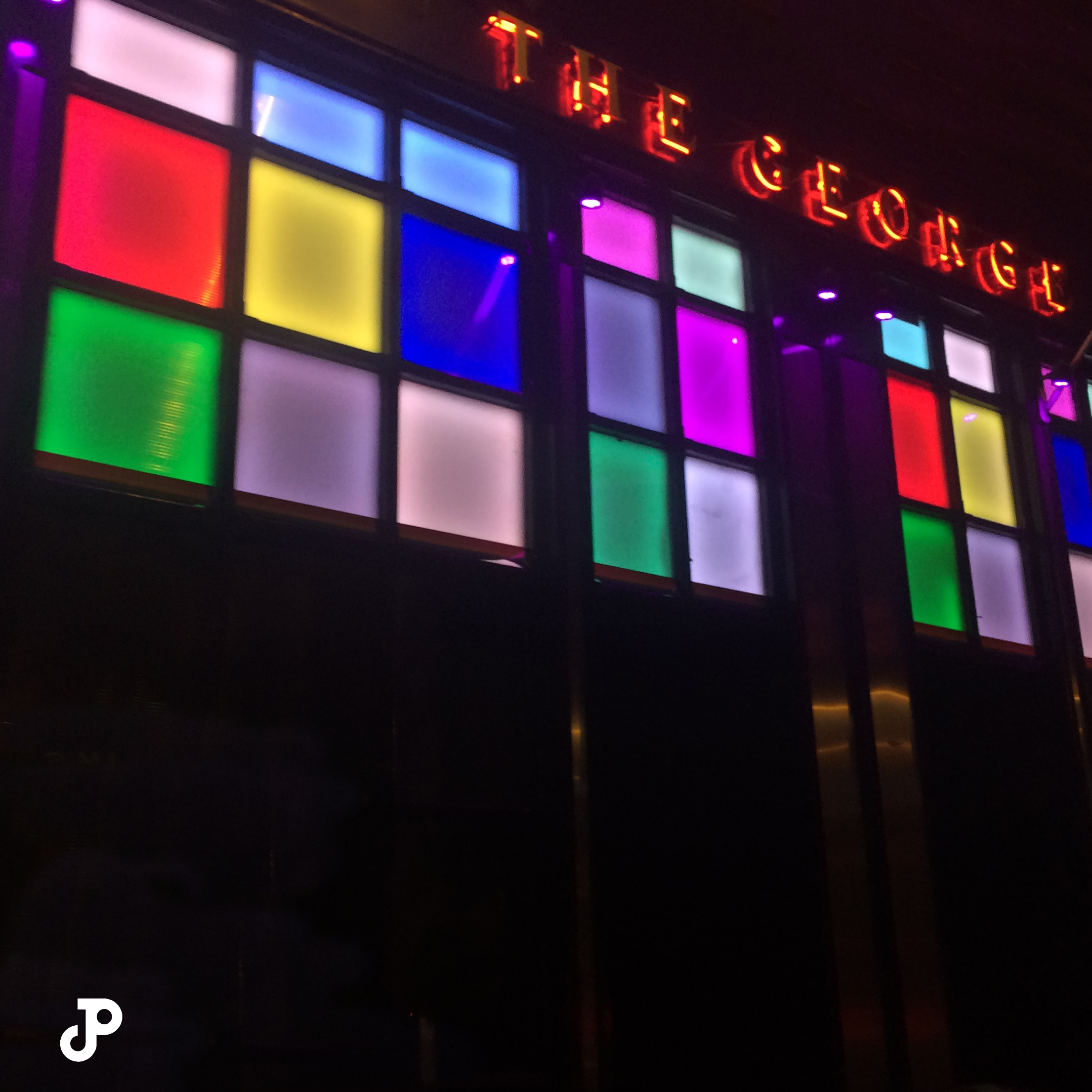 the outside of The George pub, which has colorful stained glass windows and a red neon sign