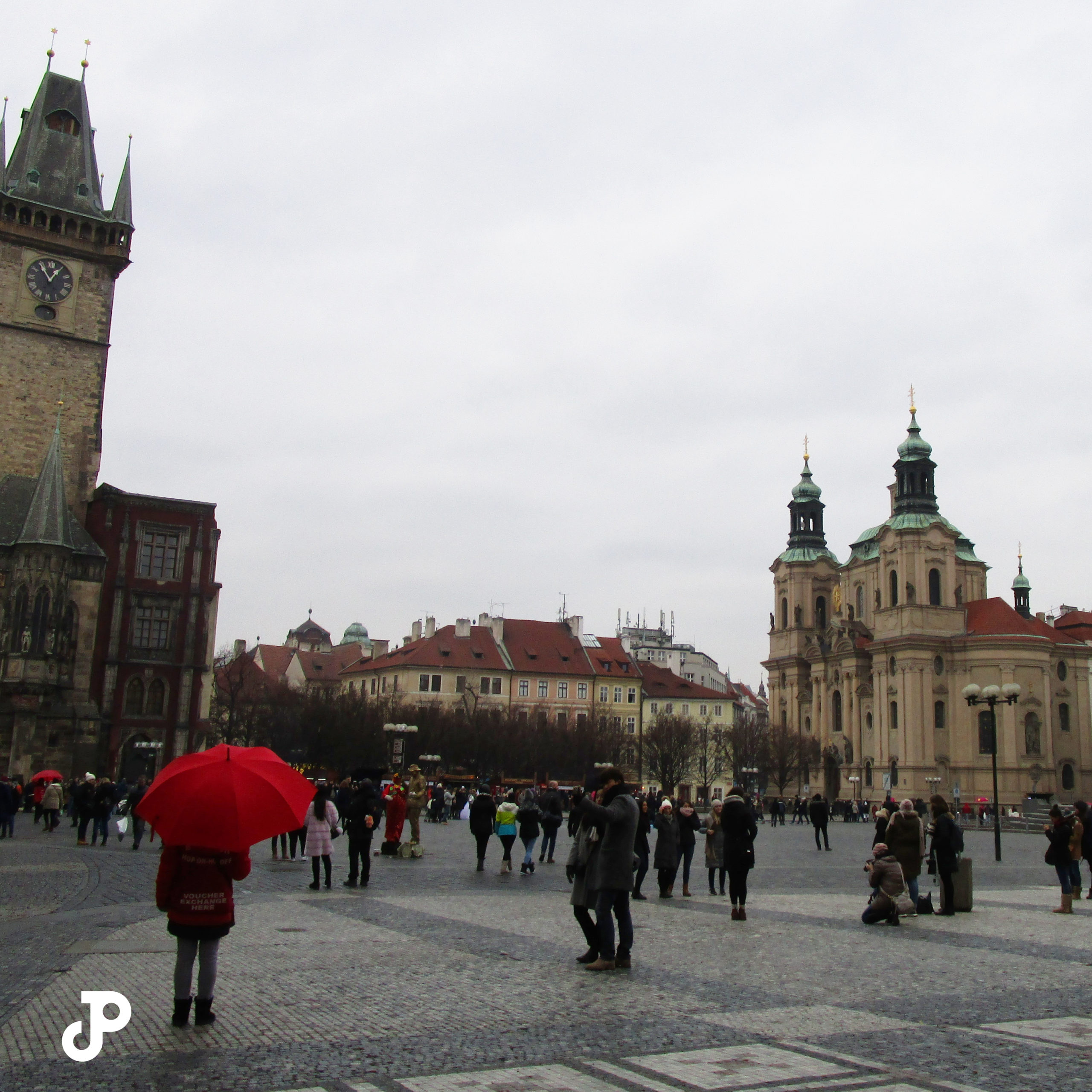 a person standing with a red umbrella in Old Town Square