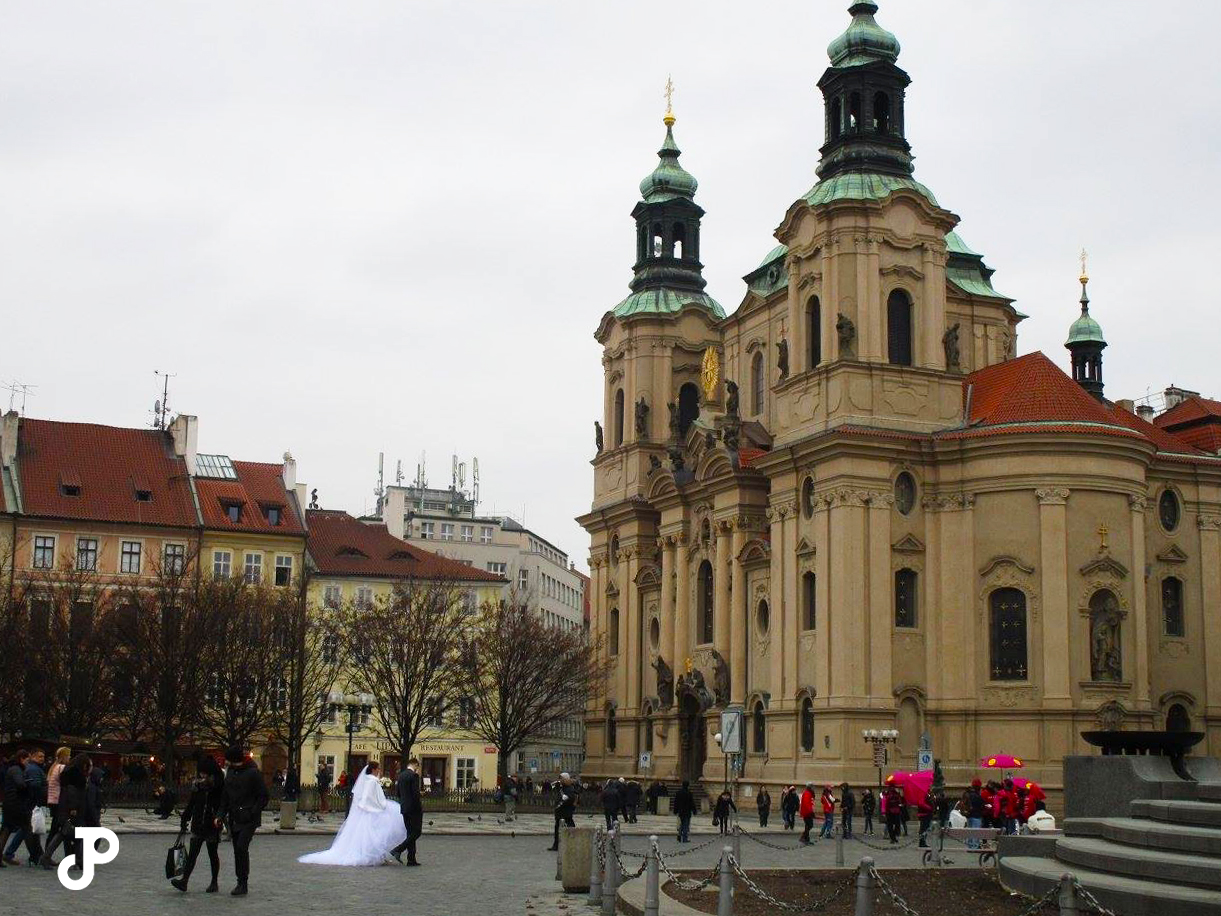 a bride and groom walking through Old Town Square