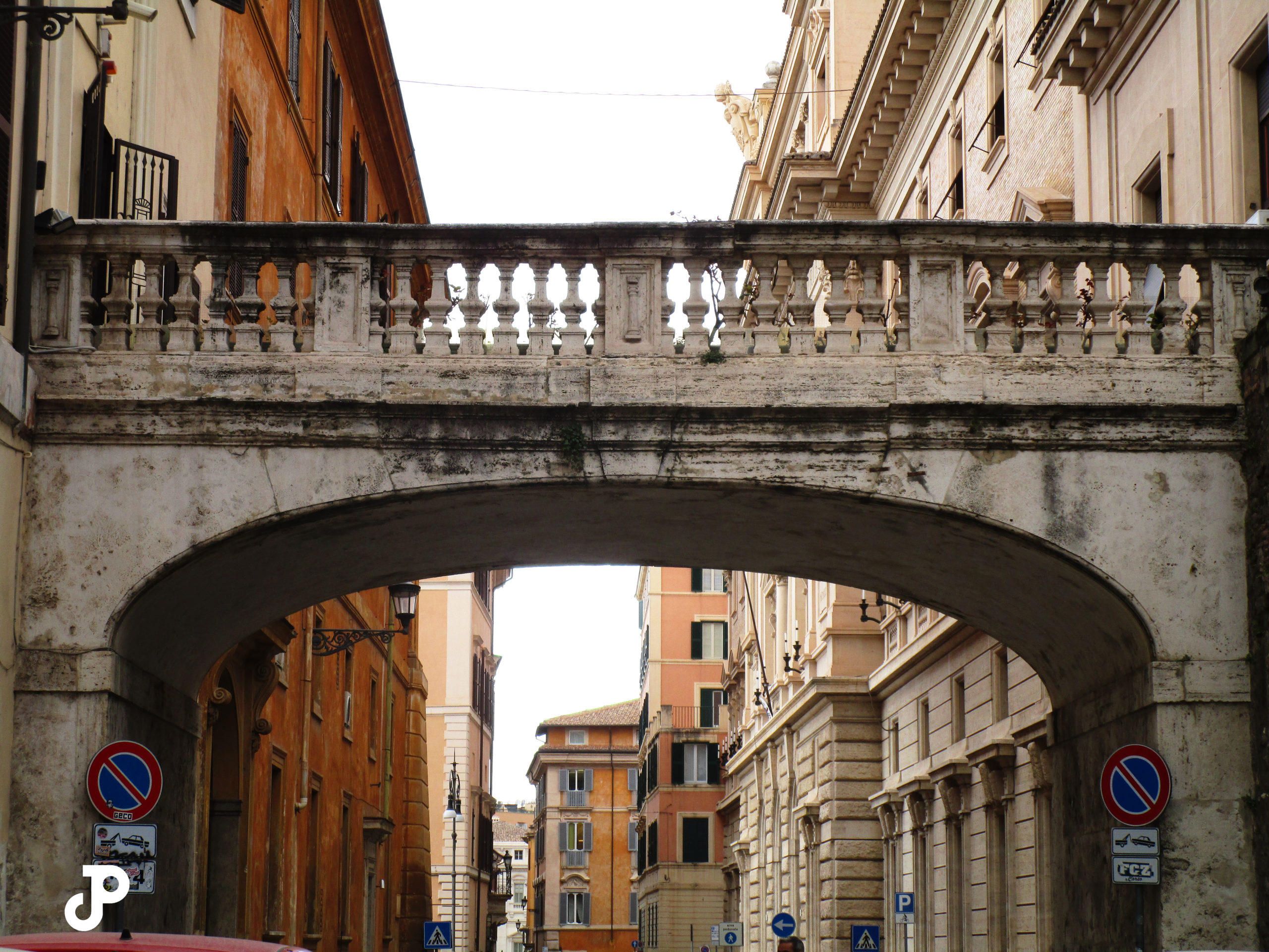 an old stone bridge spanning a road between two buildings