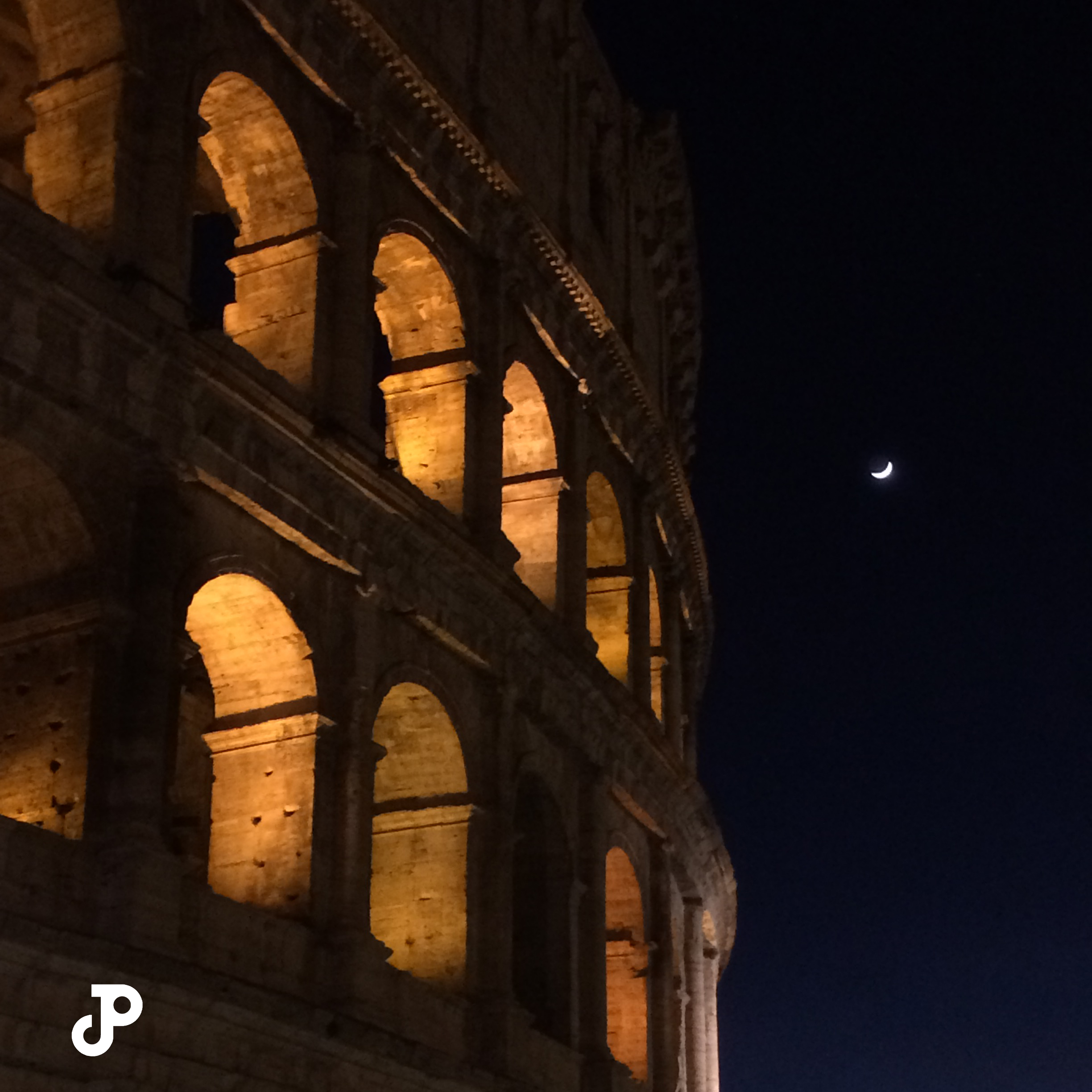 the Colosseum at night with its arches illuminated in gold light, and a crescent moon visible in the black sky