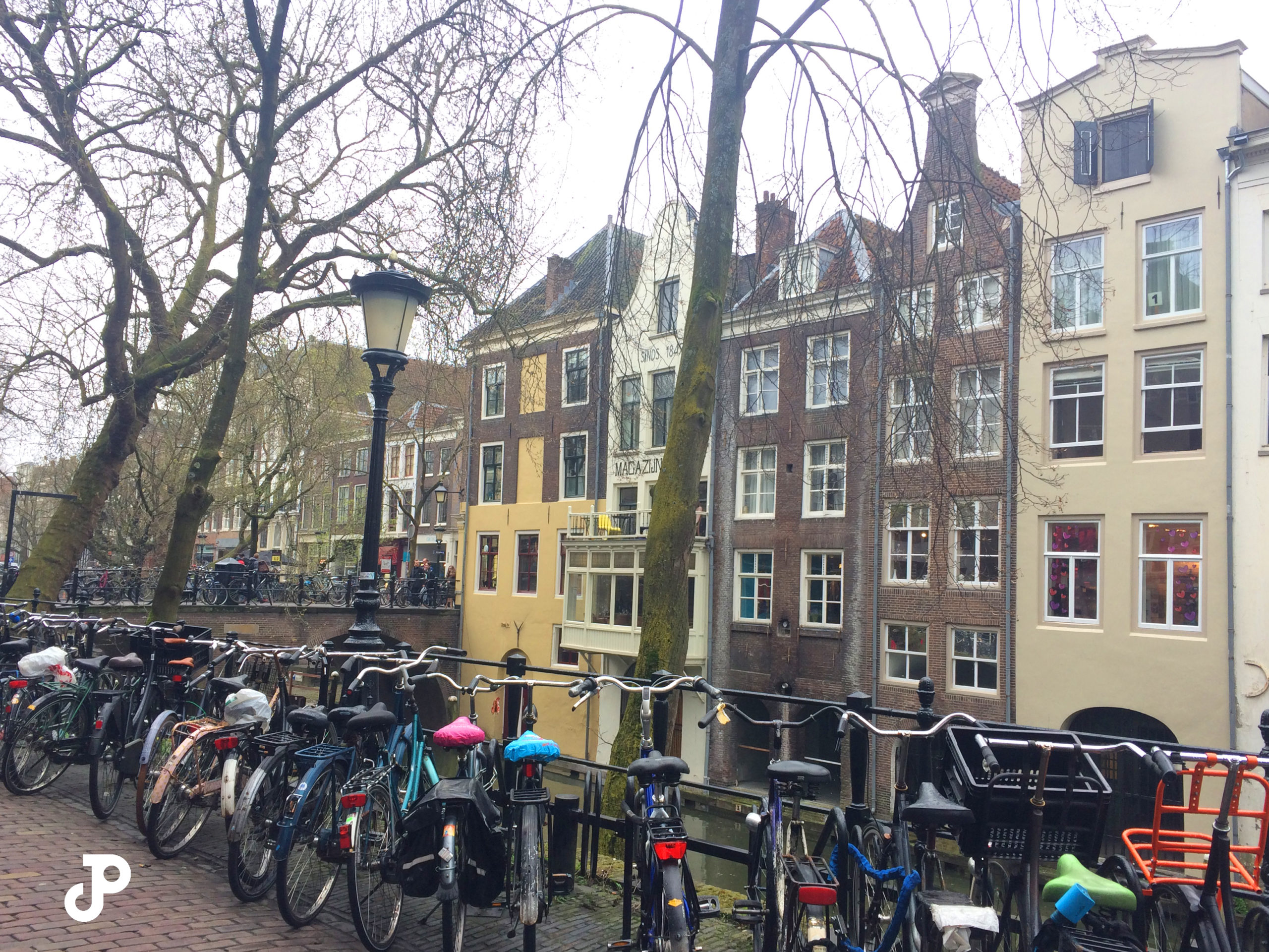 a line of bicycles along a canal with iconic narrow Dutch buildings in the background