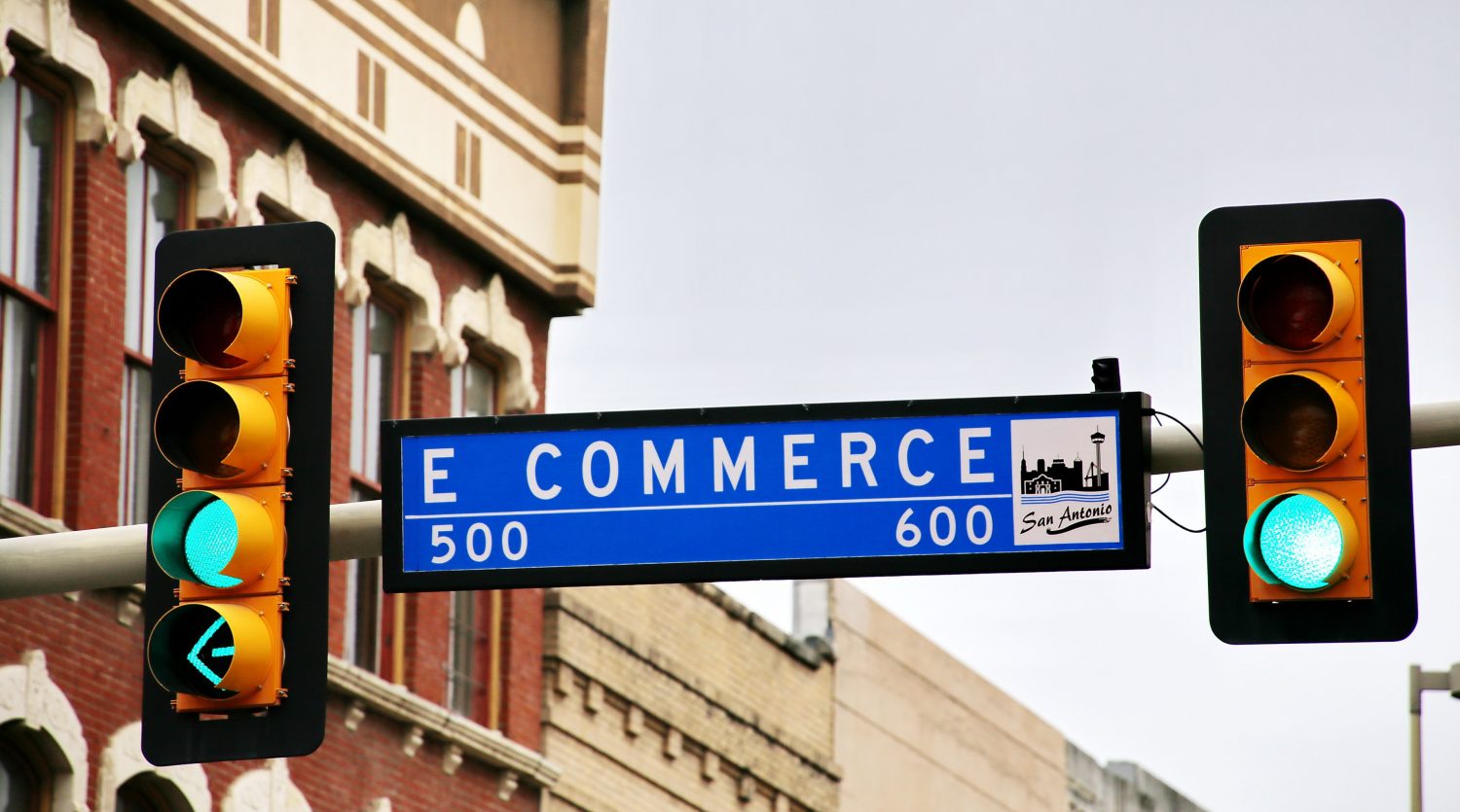 A pole of traffic lights with a road sign that reads E Commerce