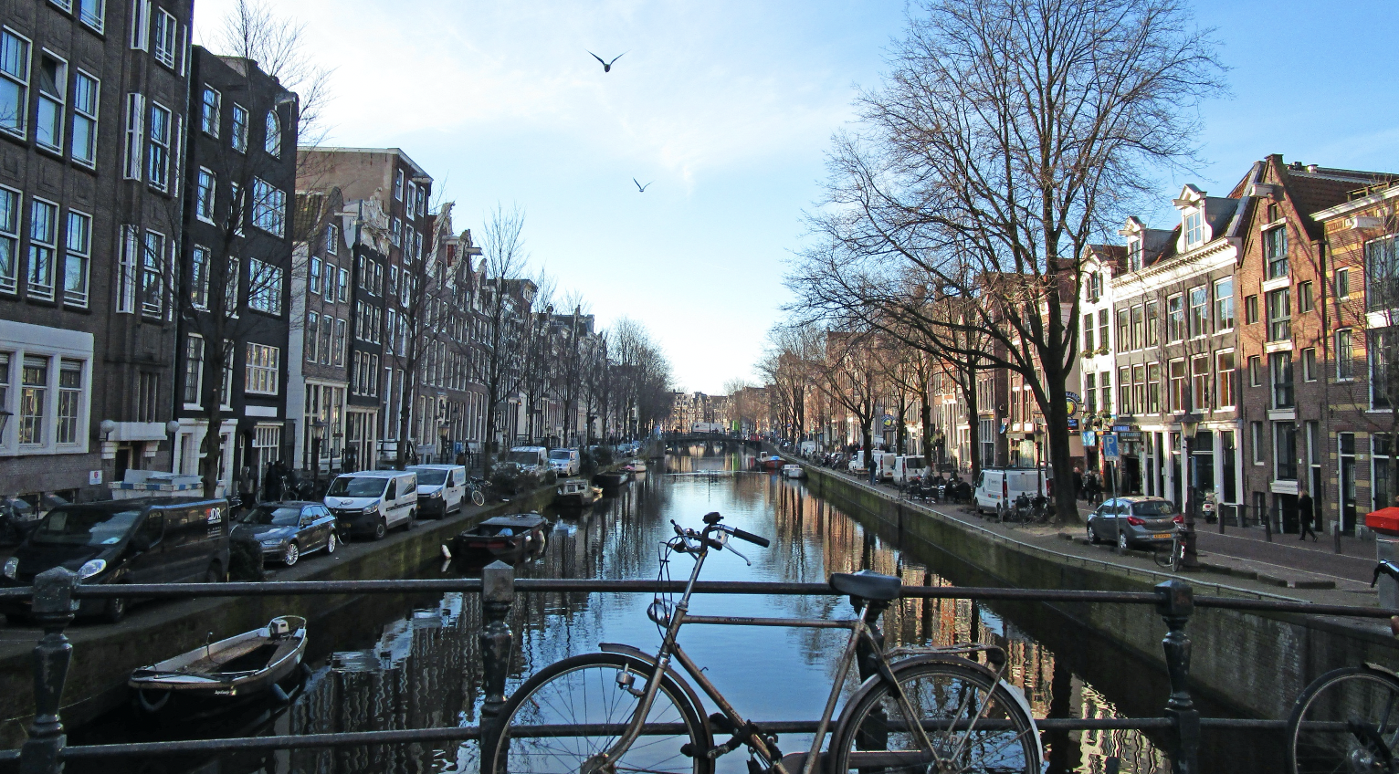 A bicycle leaning against the railing of a bridge spanning over a canal